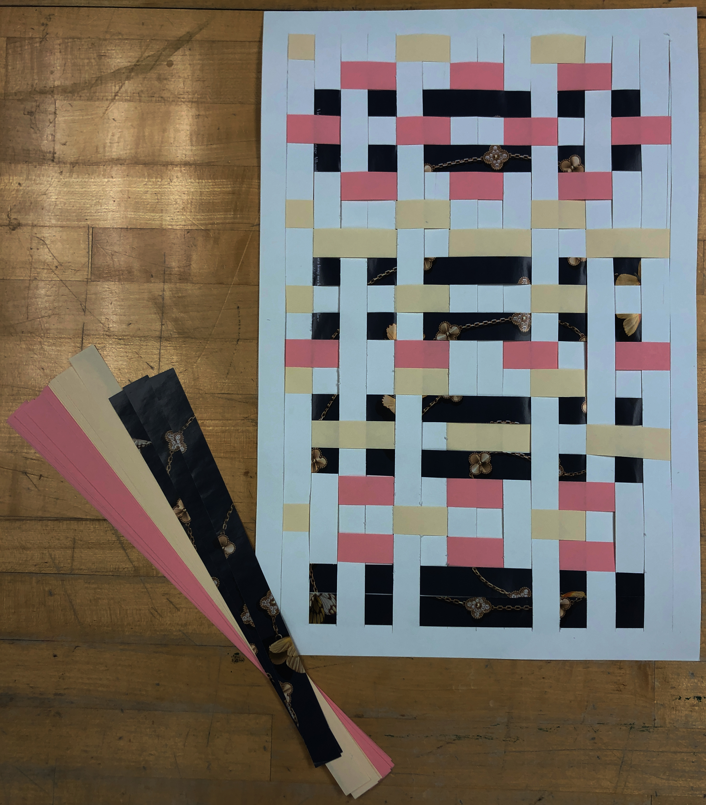 Paper weave on white paper using pink, yellow, and dark blue magazine pages to create a design.