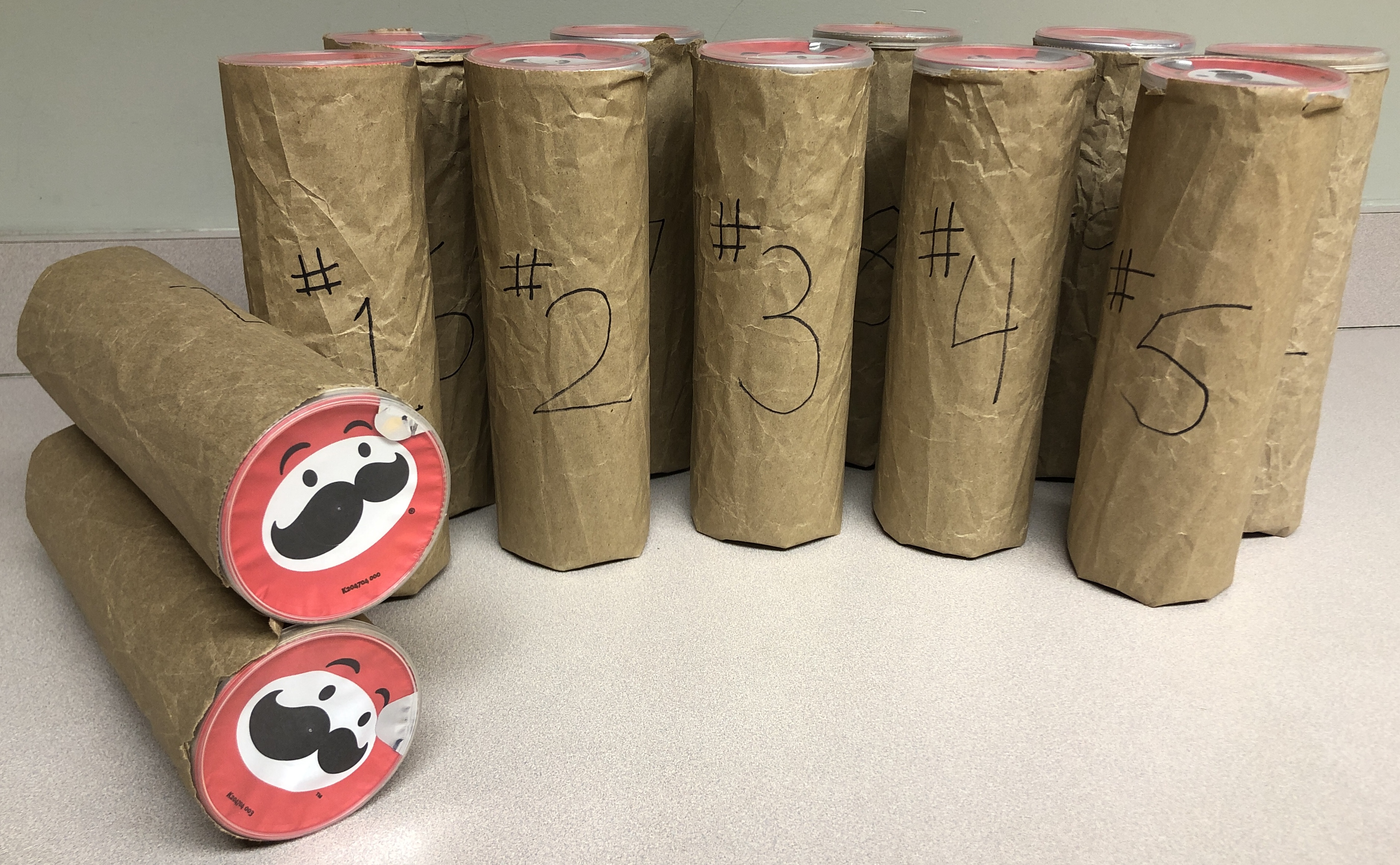 12 Pringles cans all wrapped in brown paper and numbered 1~12