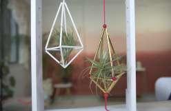 One white and one red geometric air plant hangers constructed out of plastic straws. 