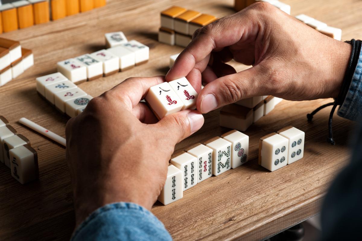 A group of people playing a tile based game known as Mah Jongg